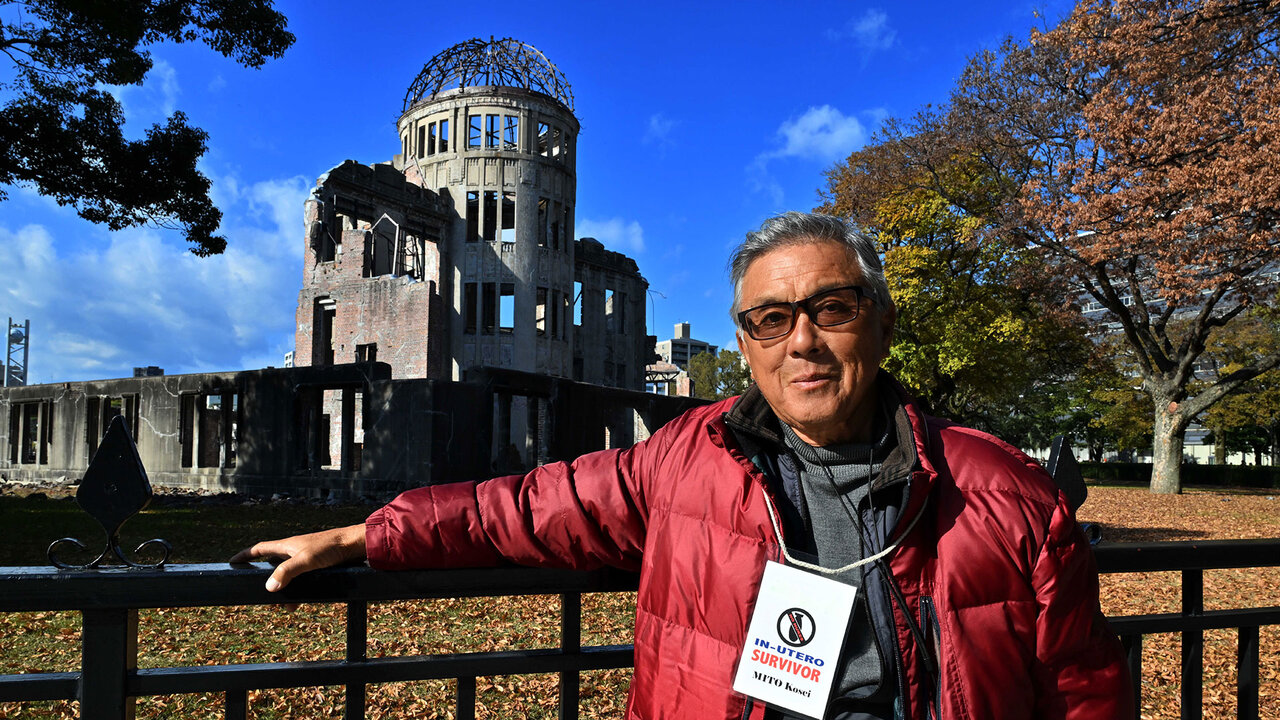 Mito Kosei, un survivant in utero pose devant le monument le Dôme de la Bombe atomique.