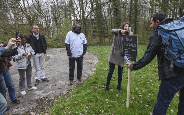 Stéphane Malek, membre du cabinet Volga et animateur de la balade au parc urbain, plante un panneau aux abords de la place, pour marquer le lieu.